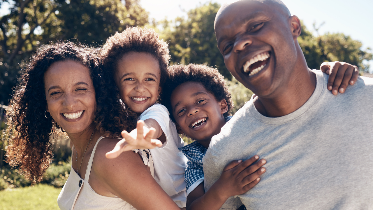 smiling family of four people outside two parents and two children african american 
