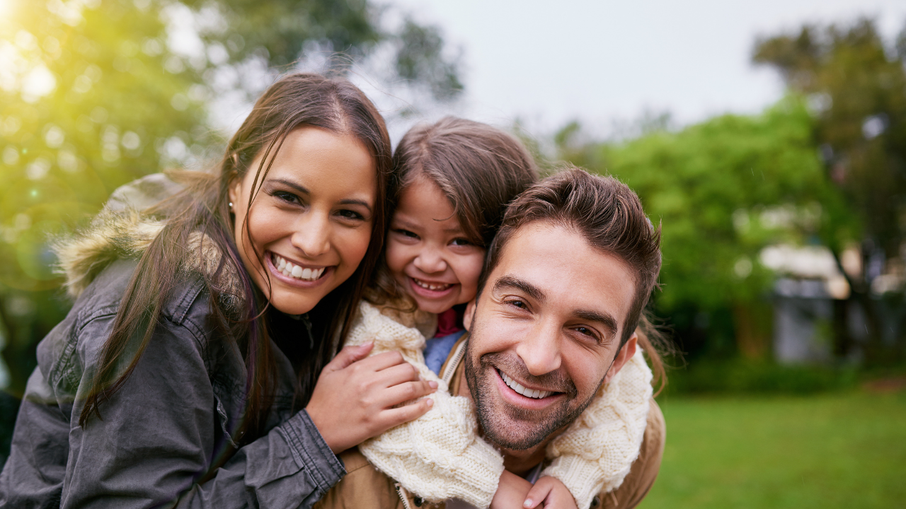 smiling family of three outside