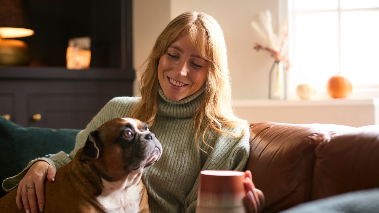woman sitting on couch with dog and cup of coffee