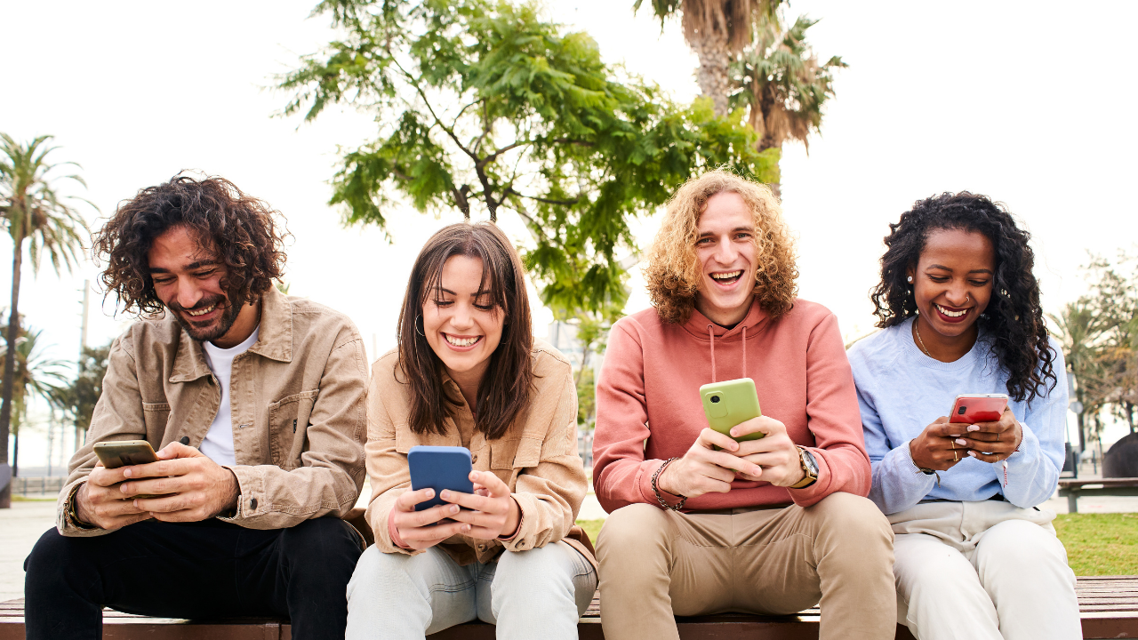 group of four people outside on cell phones 